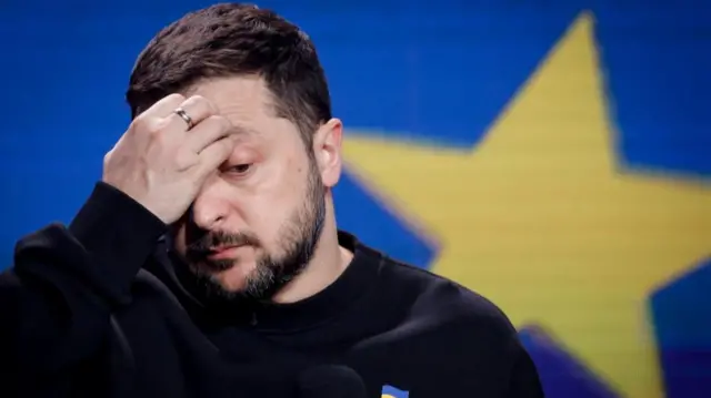 Ukrainian President Volodymyr Zelensky puts a hand to his forehead at the press conference earlier