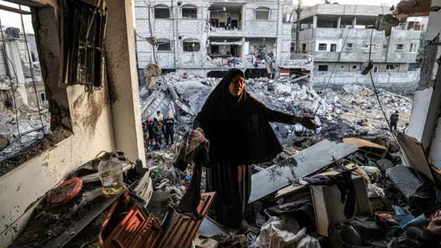 A woman inspects a destroyed building in Rafah, Gaza