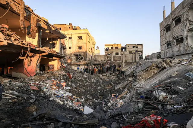 People stand on the edge of a crater in Rafah, Gaza