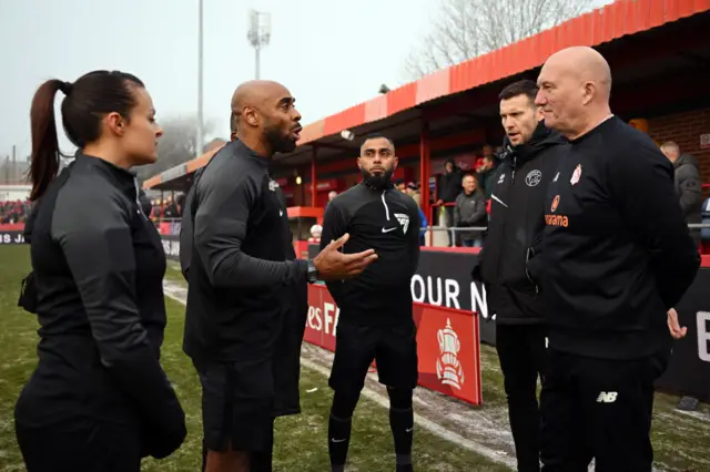 Referee speaking to Alfreton and Walsall managers to inform them of postponement