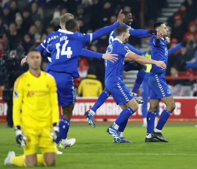 Everton players celebrate with McNeil as the Forest keeper kneels helpless on the floor.