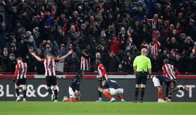 Brentford players celebrate as Luton players sink to the floor.