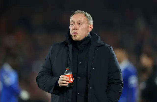 Steve Cooper walks down the touchline with a bottle of water.