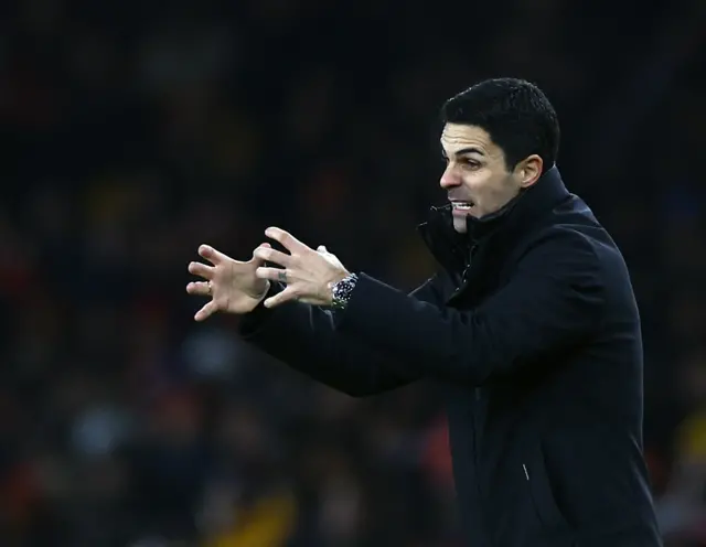 Arteta scrunches his hands together in front of him in frustration.