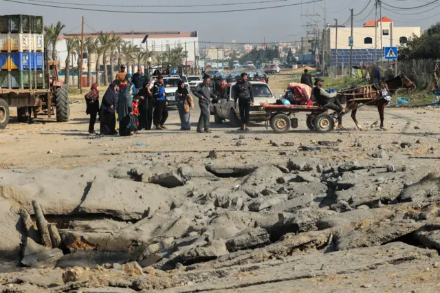 A group of Palestinians stand next to heavy damage on the main road betweeb Rafah and Khan Younis on the southern Gaza Strip