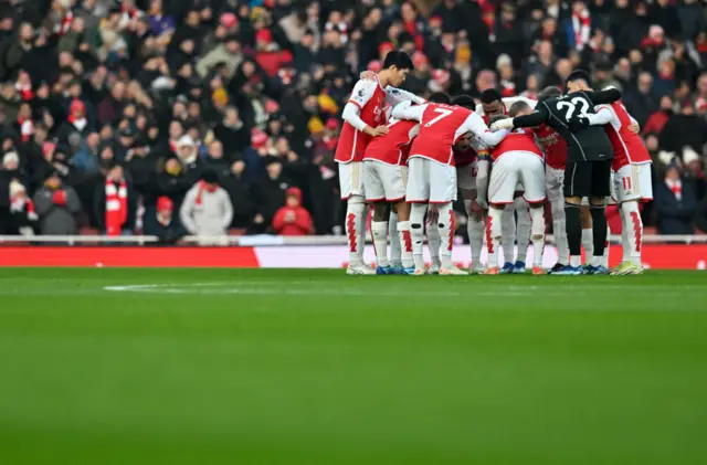 Arsenal players huddle on the pitch before kick off.