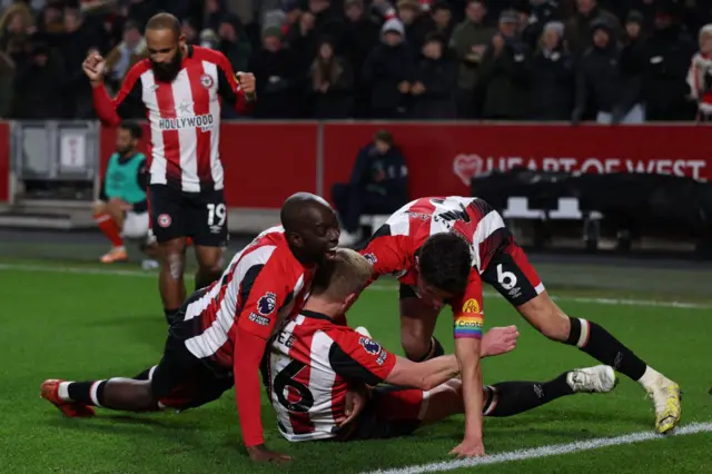 Brentford players pile on Ben Mee after his header added a second goal.