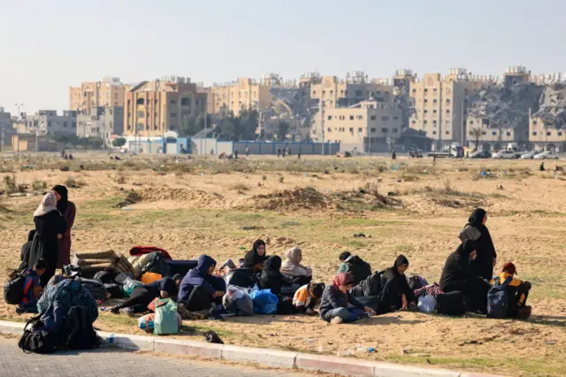 Women and children with their belongings near the Hamas Town development after it was hit in Israeli strikes