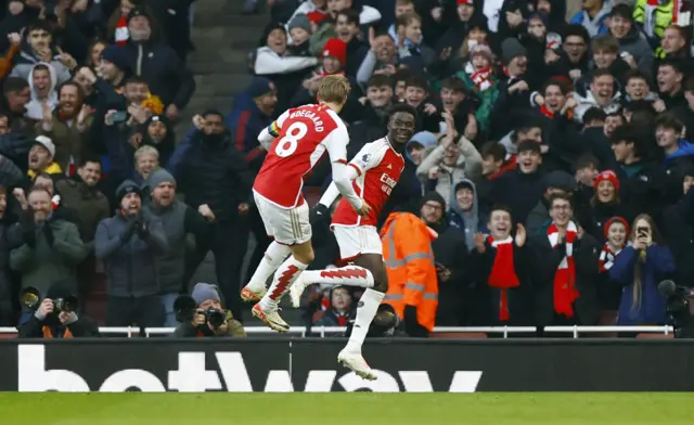 Odegaard runs to congratulate Saka on his goal.