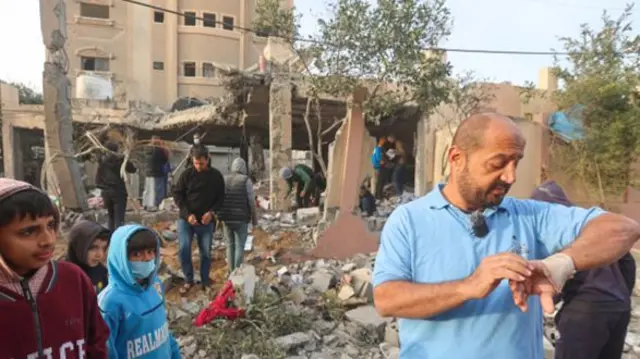 Palestinian children and adults comb through the site of a destroyed house after an Israeli airstrike