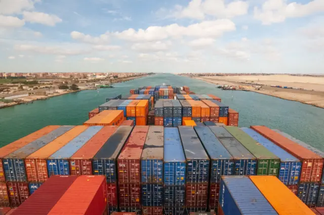 Loaded containers stacked on top of a cargo ship sailing in a canal on Janvier 20, 2017 in Suez Canal, Red sea, Egypt.