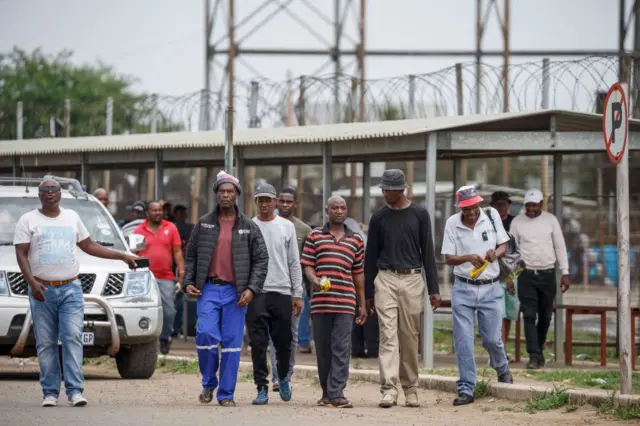 Two miners (2nd R and 4th R) look on after they resurfaced, because of medical conditions, from the underground protest at the Bafokeng Rasimone Platinum Mine near Rustenburg on December 19, 2023.