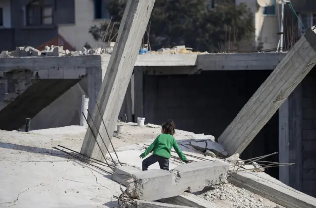 A Palestinian girl plays on the rubble of her family's destroyed house in Al Nusairat refugee camp, Gaza Strip, 20 December 2023.