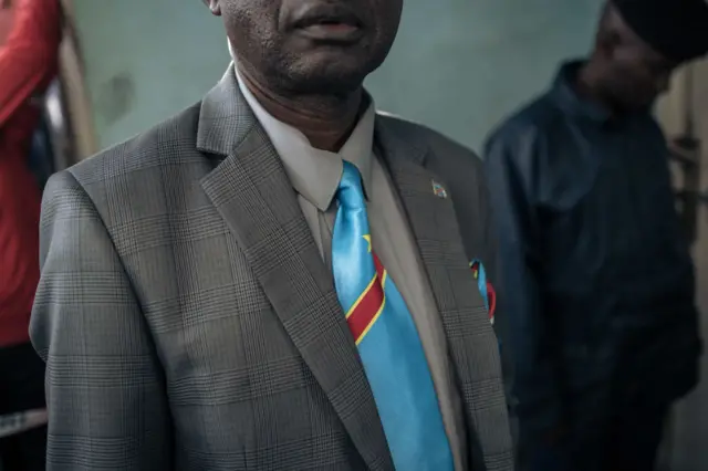 A man at a polling station wears a tie in the colours of the national flag.