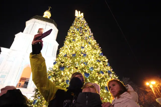 People taking a selfie by a Christmas tree