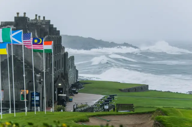 A landscape photograph showing a green coastal space with the sea in the background