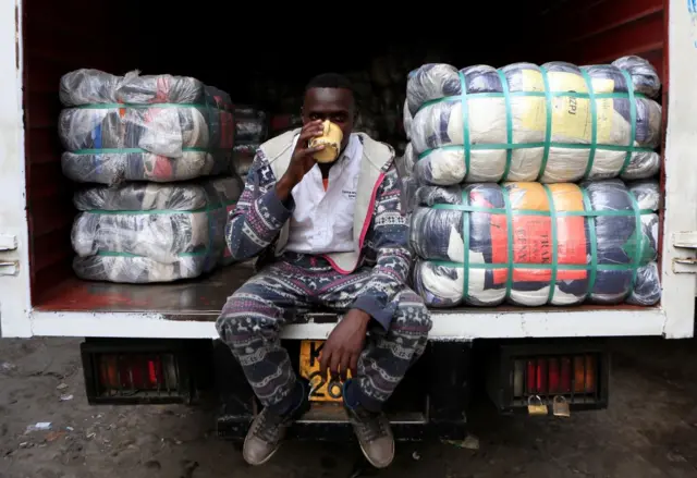 A man sits on a lorry next to bales of clothing in 2017.