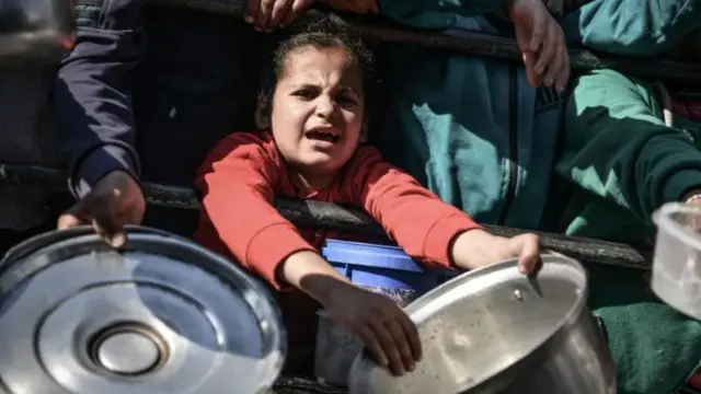 A child holds out a pan for food in Gaza