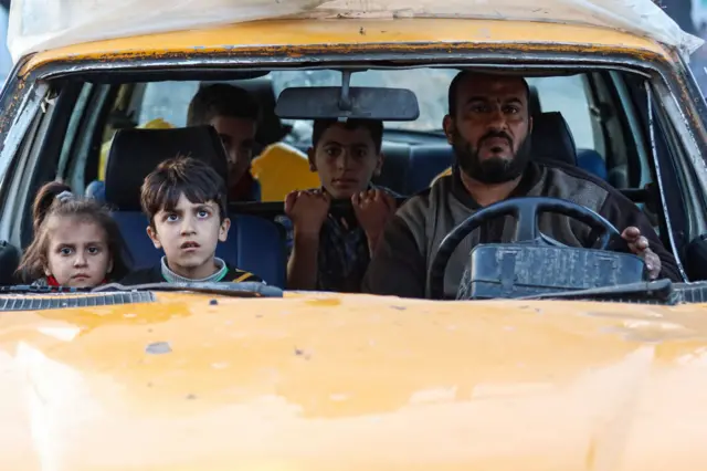 A man driving a yellow car with four children