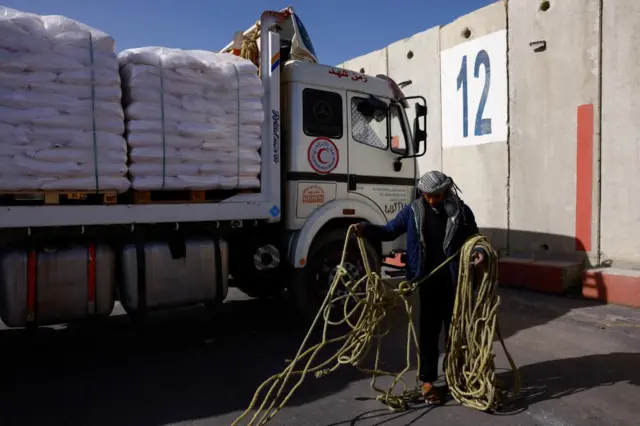 An Egyptian aid truck driver sorts out ropes that are used to secure the aid on the back of a truck, at the cargo inspection area before going to Gaza,