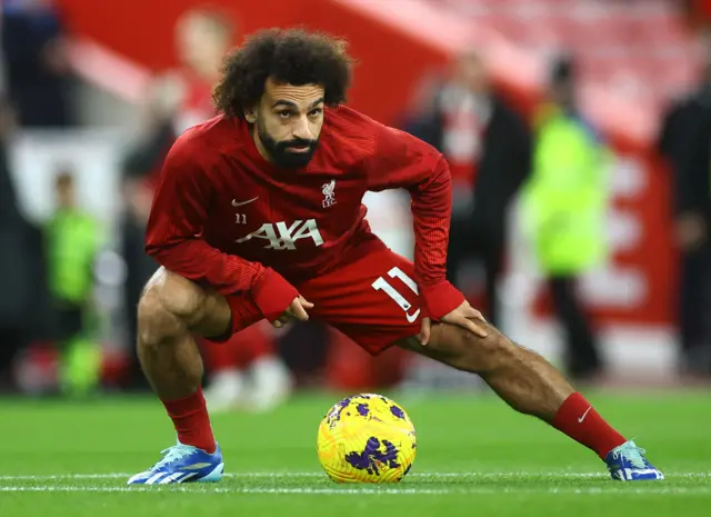 Salah warms up with a stretch at Anfield.