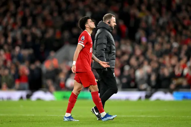 Diaz looks to the heavens as he walks off alongside a physio.