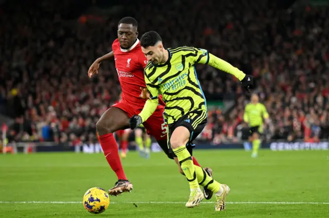 Konate and Martinelli run for the ball on the wing.