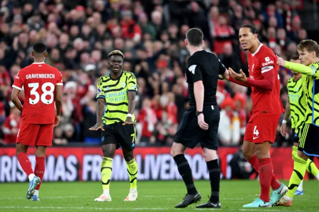 Saka appeals to the referee as Liverpool players ask for him to be sent off.