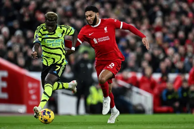 Saka and Gomez go head to head for the ball.