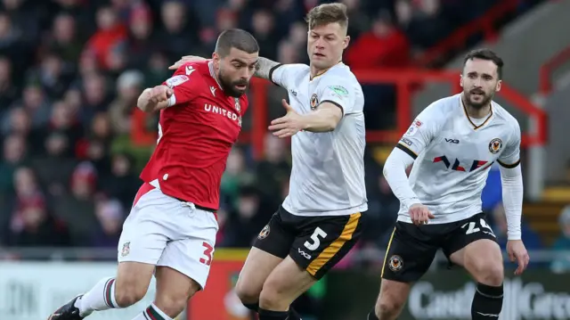 Wrexham and Newport players challenge for the ball