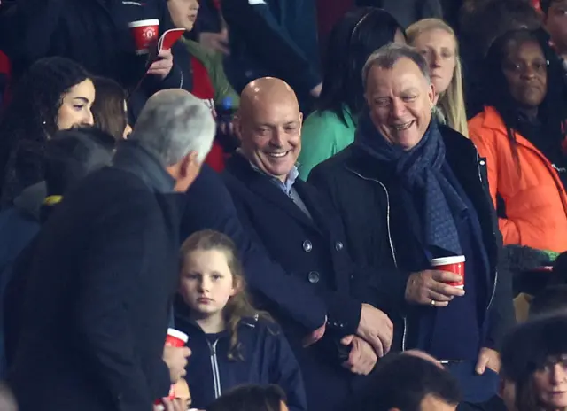 Dave Brailsford laughs with colleagues as he takes his seat in the stands.