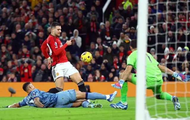 Dalot's cross evades the challenge of Carlos but not the gloves of Martinez.