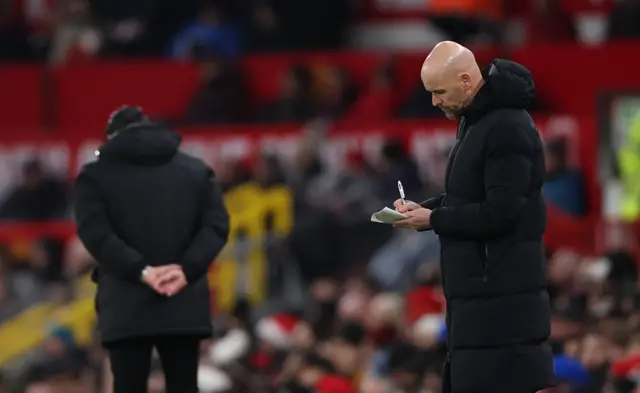 Ten Hag writes a note on the touchline.