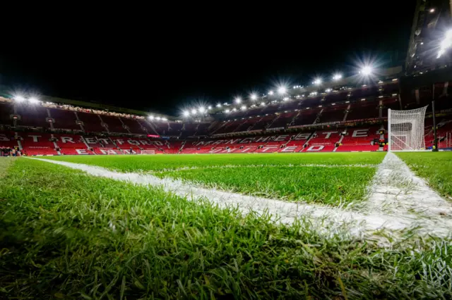 The Old Trafford pitch stands ready under floodlights.