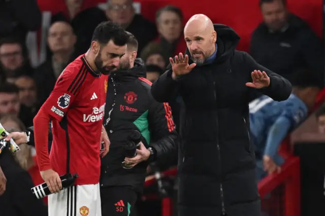 Fernandes and Ten Hag discuss tactics during a pause in play.