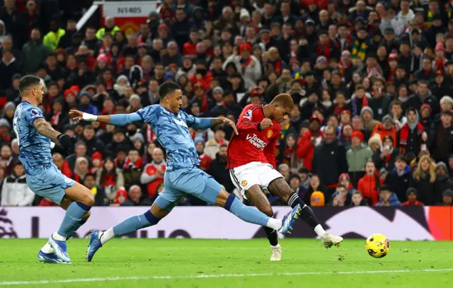 Rashford takes aim from the angle as he is closed down by two defenders.