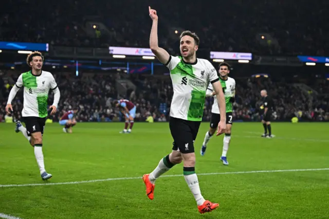 Jota waves and cheers in front of the away fans after scoring Liverpool's second goal.