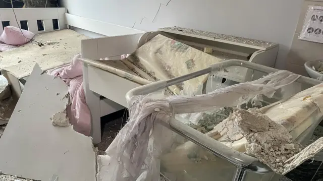 A baby's cot with rubble strewn over it