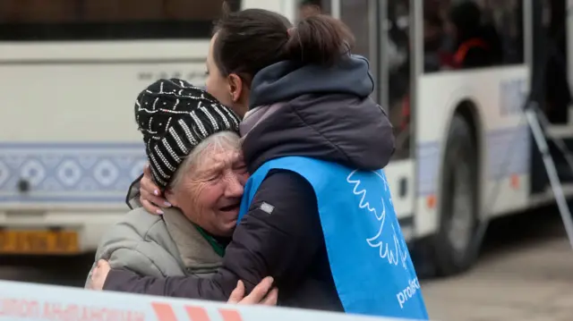 Crying elderly woman is embraced by another woman