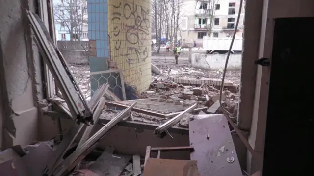 Looking through a blown out window into a street filled with debris