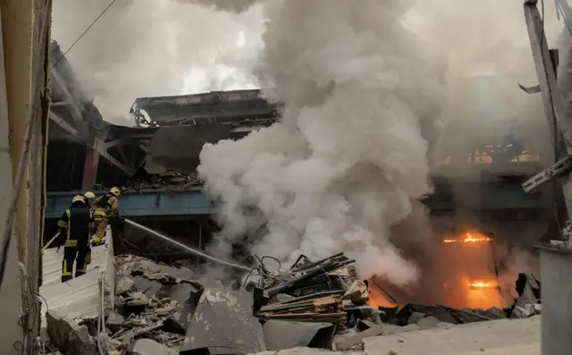 Emergency workers battle a fire following a rocket attack on a factory in Kharkiv