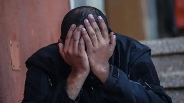 A man mourns with his head in his hands after an Israeli air strike in Khan Younis in the southern Gaza Strip