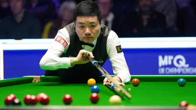 Ding Junhui plays a shot with the rest