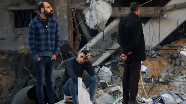 Men stand amidst rubble