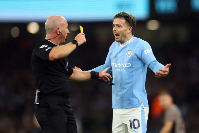 Jack Grealish is shown a yellow card by referee Simon Hooper