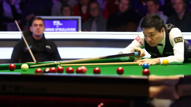 Ding Junhui plays a shot with the rest