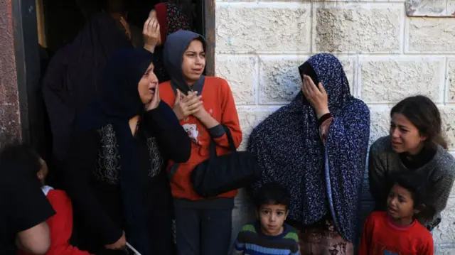 Women and children outside a house