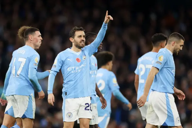 Bernardo Silva points to the stands as he is congratulated by teammates.