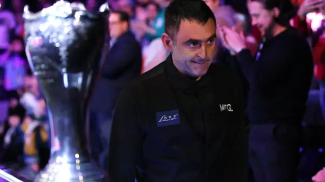 Ronnie O'Sullivan walks past the UK Championship trophy