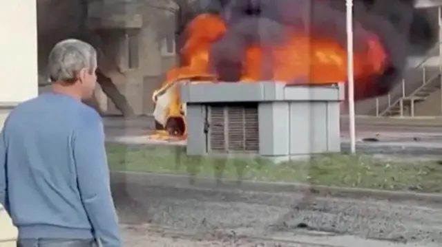 A man stands near a burning car in Belgorod